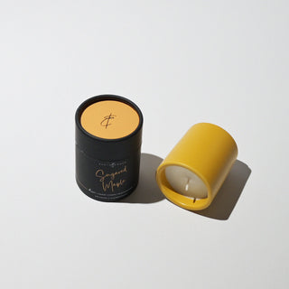 A yellow votive candle with canister labeled 'Sugared Maple' with a white background