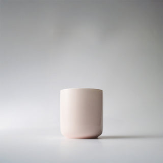 Light pink glass candle container against a white background