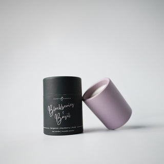 Lavender colored ceramic container with candle and holder labeled 'Blackberries & Basil' against a white background