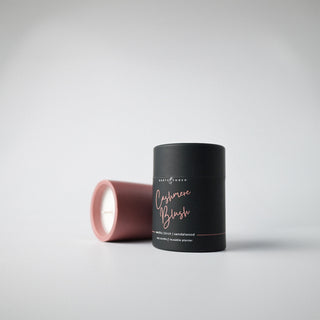 A blush colored container with a candled and holder labeled 'Cashmere Blush' against a white background