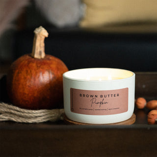 10 oz candle labeled 'Brown Butter Pumpkin' with a pumpkin and beads on a dark surface