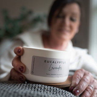 Person holding a 10 oz candle labeled  'Eucalyptus Lavender' with a blurred background