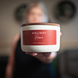 10 oz candle with a 'Holiday Home' label held by a person against a blurred background